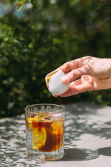 Hand pouring coffee into glass with orange slice