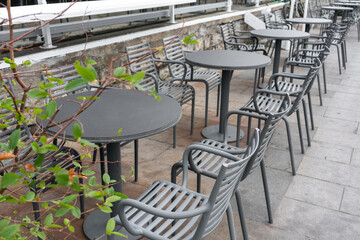 An empty street cafe or restaurant terrace with gray plastic tables and chairs, no people.