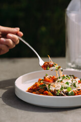 Hand using fork eating colorful healthy fresh meal