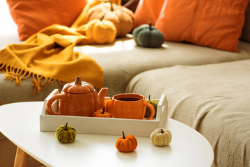 Autumnal living room decor with pumpkins, teapot, tea cup and cozy blankets.