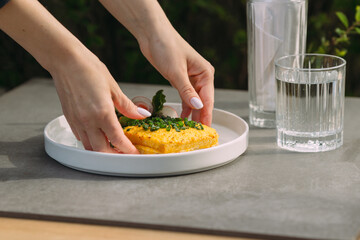 Hands serving a delicious omelet with fresh chives