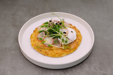 Savory vegetable pancake with poached egg and fresh herbs
