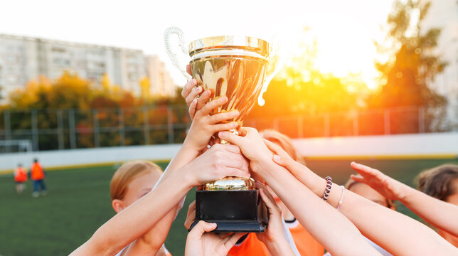 Womens childrens football team celebrating victory with trophy
