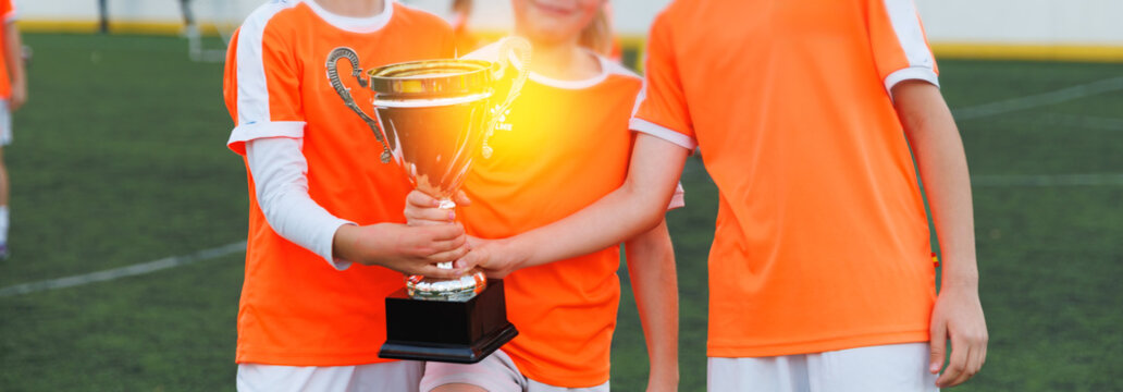 Girls junior soccer team holding trophy on field - Powered by Adobe