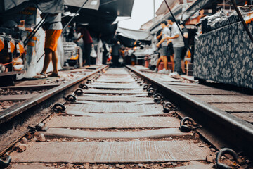Railway track with people crossing it in a market in Thailand