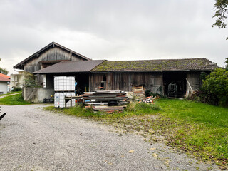 Old wooden barn with lumber stacks and water tank in a rural German farmyard