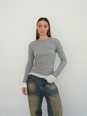 Stylish Model Posing in Casual Outfit Featuring Slim-Fit Top and Relaxed Jeans Against a Clean...