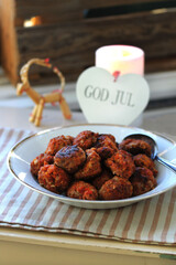 Swedish Christmas meatballs on plate with a candle and “God Jul” decoration