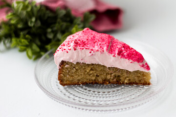 Slice of cake with pink frosting on glass plate