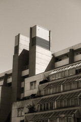 Obraz premium Brutalist concrete building with tiered glass sections in sepia.