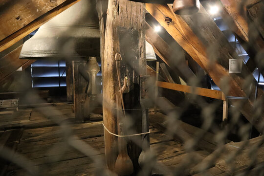 Estructura de madera en torre con grandes campanas met&aacute;licas, luz filtrada y vista protegida por malla.