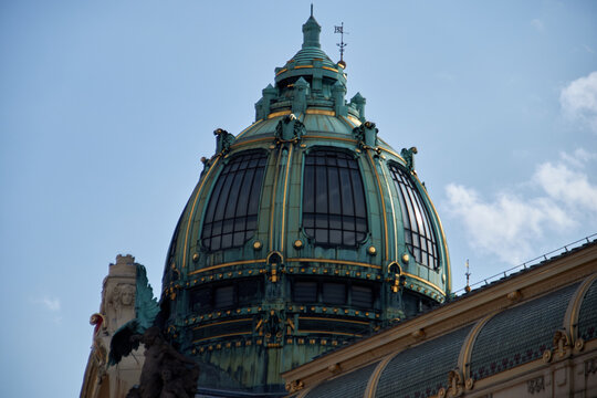 C&uacute;pula ornamentada con p&aacute;tina verdosa, detalles dorados y ventanales arqueados, coronada por peque&ntilde;as agujas bajo un cielo claro.