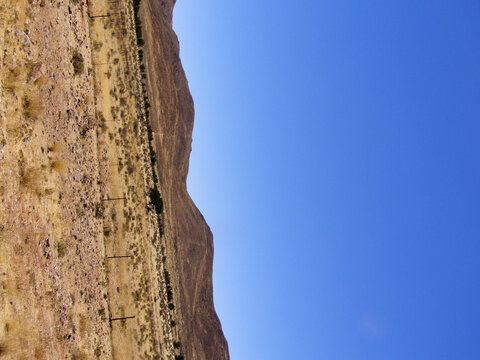 Detalle de ladera rocosa y &aacute;rida contra un cielo azul intenso