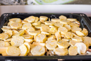 Place the sliced potatoes, seasoned and ready for baking, on a baking sheet