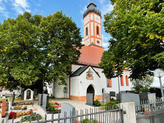 Historic church St. Sebastian Puch in Furstenfeldbruck, Germany with clock tower and lush cemetery surrounding the building