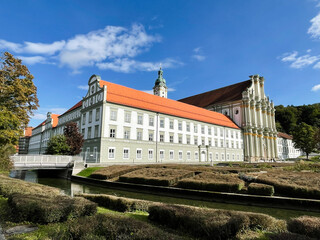 Historic Baroque complex in Furstenfeldbruck, Germany with orange roofs, canal, and grand church facade