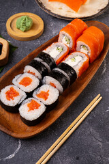 A vibrant assortment of fresh sushi, including nigiri, rolls, and sashimi on grey background vertical photo