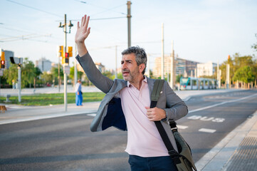 Man hailing taxi or bus on city street