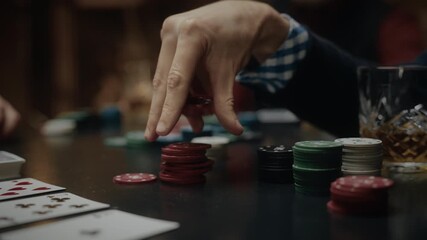 Male hand holding poker chips above the game table