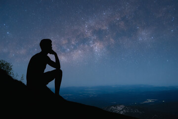 Obraz premium silhouetted male figure contemplating vast star-filled night sky from mountain ridge
