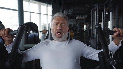 Portrait of an older man hardly training in a training machine in a gym