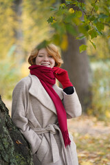 Portrait of a Girl in an Autumn Park in Coat and Red Scarf