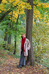 Girl in Autumn Park in Coat and Red Scarf
