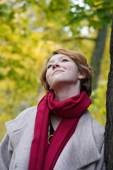 Portrait of a Girl in an Autumn Park in Coat and Red Scarf