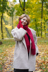 Portrait of a Girl in an Autumn Park in Coat and Red Scarf