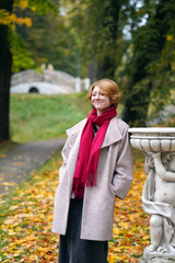 Portrait of a Girl in an Autumn Park in Coat and Red Scarf
