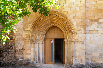 Romanesque portal with archivolts and a modern wooden door at the Monastery of San Andrés de Arroyo, Palencia, Spain
