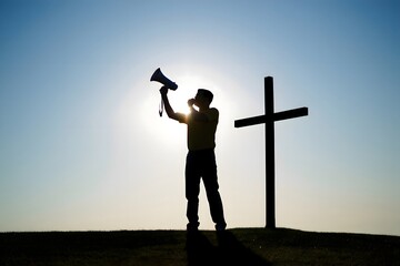 Man with megaphone by cross silhouette against bright sky spreading the word of god far and wide