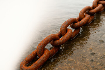 Fototapeta premium A rusty chain lies in the water. Space for text.