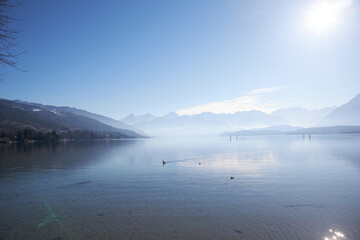 Fototapeta premium Lago alpino con reflejos solares y boyas flotantes en día despejado