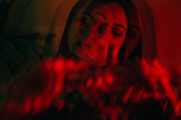 Dreamy portrait of a brunette with bright red flowers in a red green glow with a triple lens and long exposure