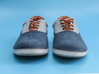 Denim male sneakers on a blue background.