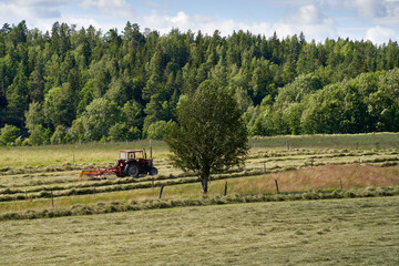 "Harvesting Hay in Rural Sweden: Tractor Working in the Countryside Near Håverud"