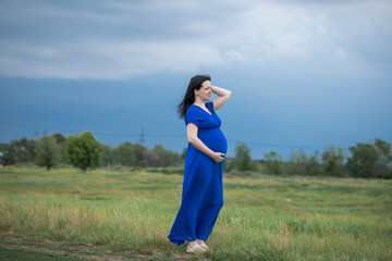 Full length portrait of a pregnant woman in nature