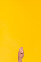 Hand gesture with vibrant yellow backdrop highlights creativity and expression in artistic design
