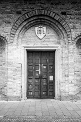 Historic Wooden Door with Arched Brick Frame and Heraldic Emblem