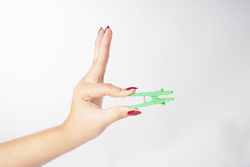 A hand holding a green clothes clamp on a white background