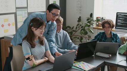 Middle-aged short-haired female teacher guiding her students, using laptops during IT class in school - Powered by Adobe