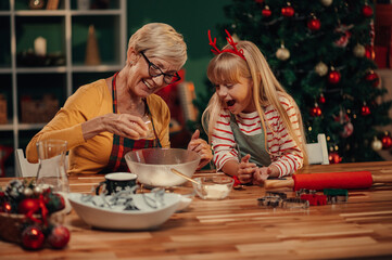 Grandmother and granddaughter preparing christmas cookies dough