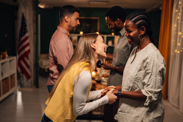 Friends holding hands and laughing at thanksgiving dinner