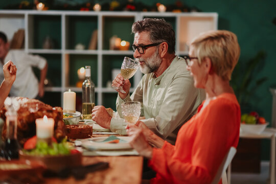 Senior couple enjoying wine at thanksgiving dinner with family