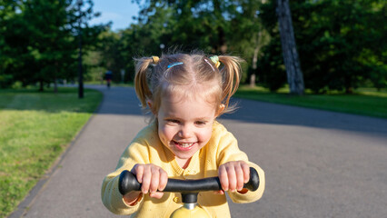 Toddler on scooter. Yellow scooter ride girl. Child park activity summer.