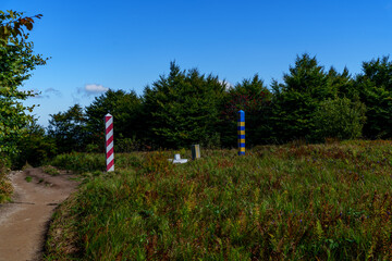 Sunny border meadow with Poland and Ukraine posts beneath blue sky