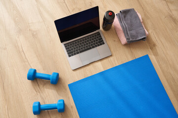 Top view of laptop , dumbbells, fitness mat on the floor. Concept of yoga or fitness online class