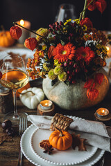 Fall table decoration with pumpkins, wine. Family cozy thanksgiving dinner arrangement indoors at...