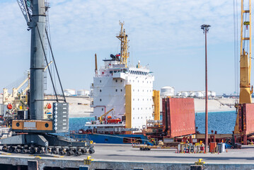 Bulk carrier ship docked at a port terminal with its cargo hold open. Puerto Angamos, Chile.